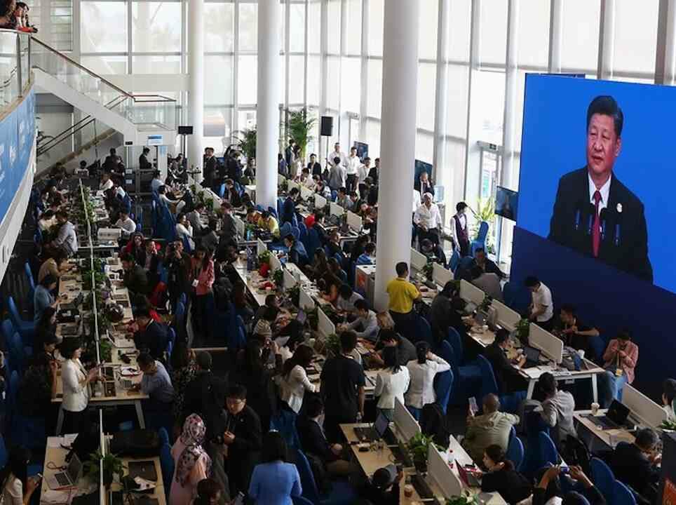 Journalists watch a screen showing a live image of China's President Xi Jinping as he delivers a speech at the Boao Forum on April 10, 2018.