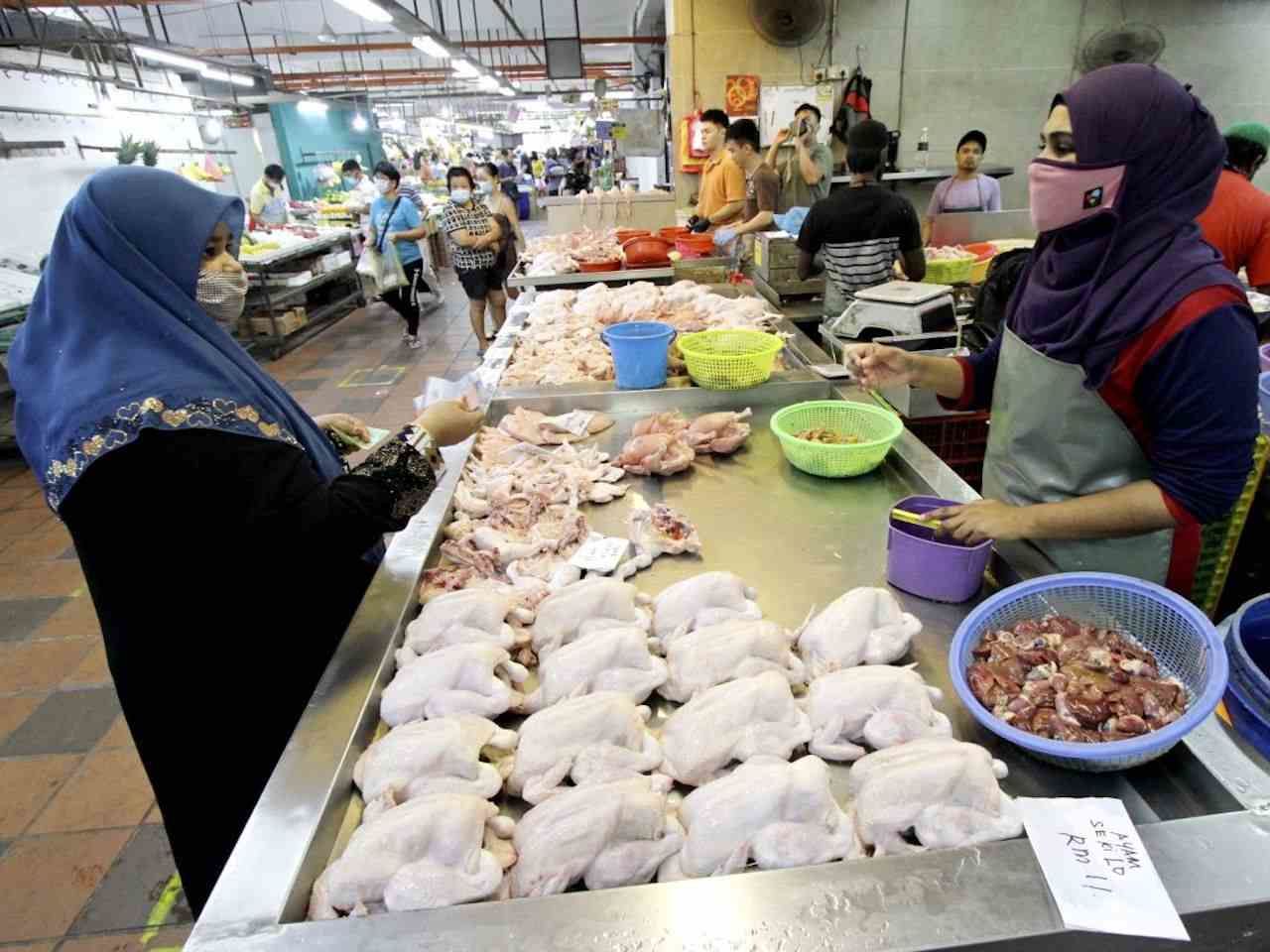 The customers are purchasing fresh chicken at Batu Lanchang wet market in Malaysia.