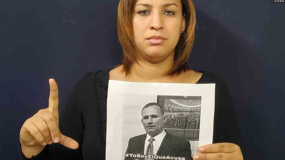 Ms. Nelva Ismarays Ortega Tamayo, wife of the Cuban opposition leader Mr. José Daniel Ferrer is holding a photo of her husband and shows an L letter for Liberty an informal sign of Cuban freedom fighters.