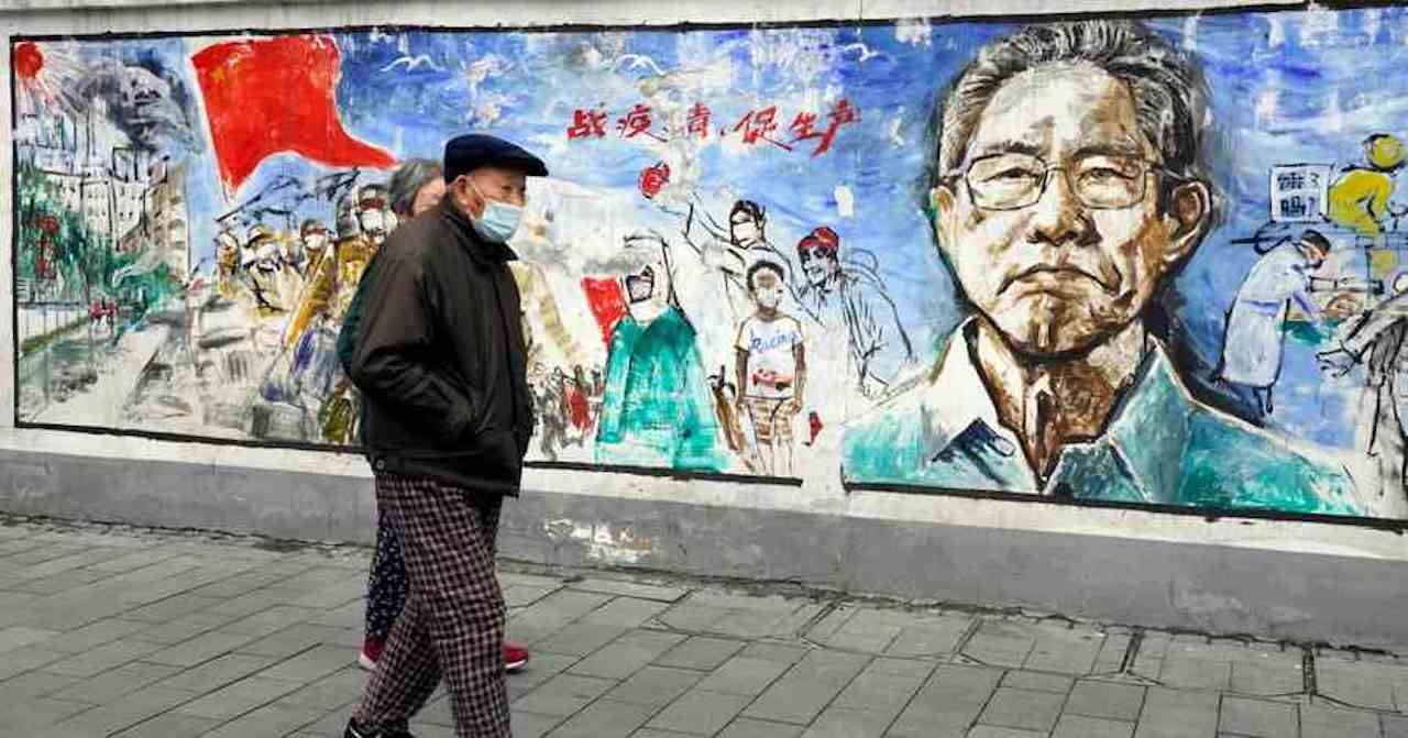 A man wearing face mask passes a grafitti wall with tribute to Chinese doctors in Wuhan on April, 12, 2021.